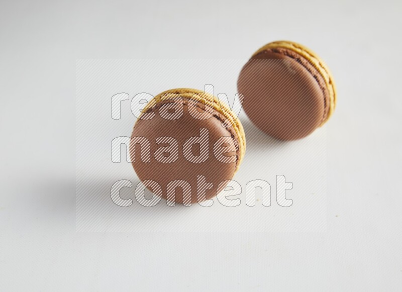 45º Shot of two Yellow and Brown Chai Latte macarons on white background