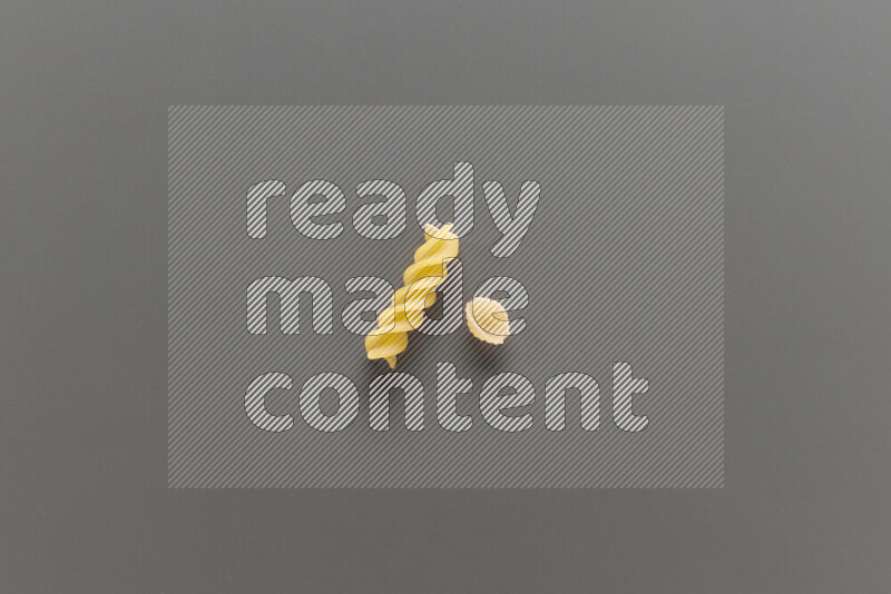Shells pasta with other types of pasta on grey background