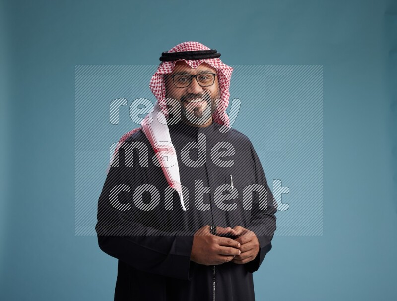 Saudi Man with shimag Standing Interacting with the camera on blue background