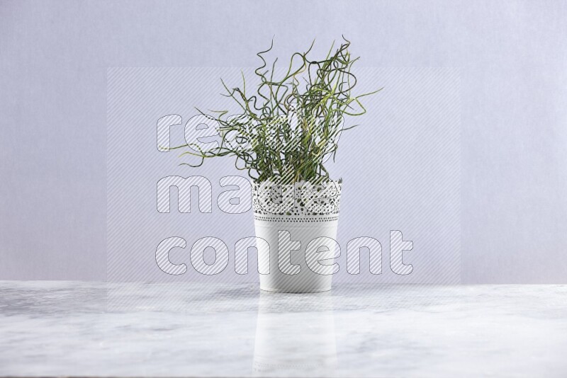Green artificial plant in white decorative pot on grey marble background