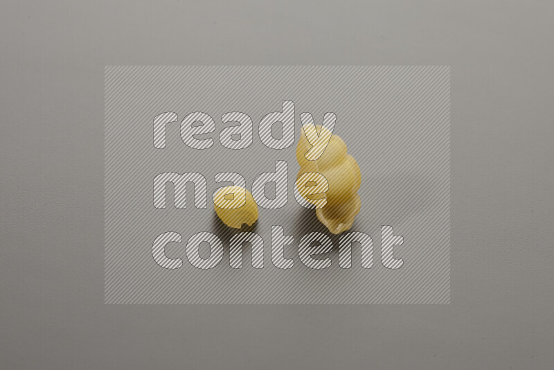 Shells pasta with other types of pasta on grey background
