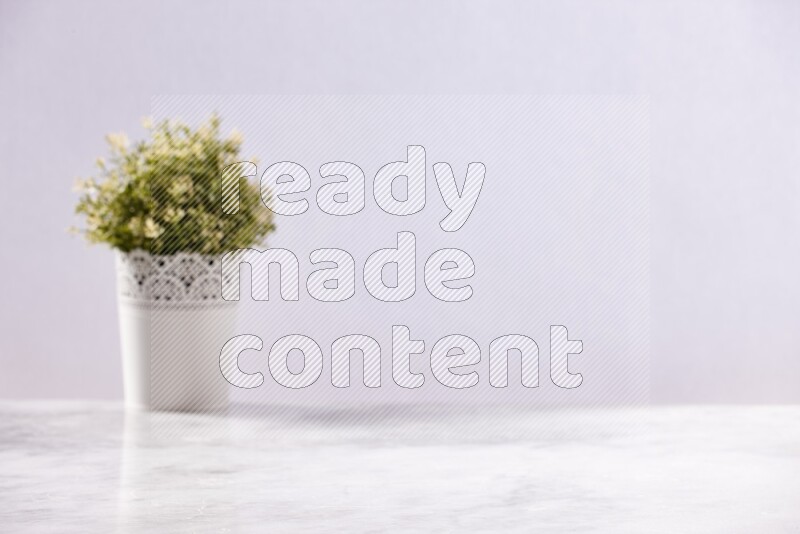 Artificial plant in white decorative pot on grey marble background