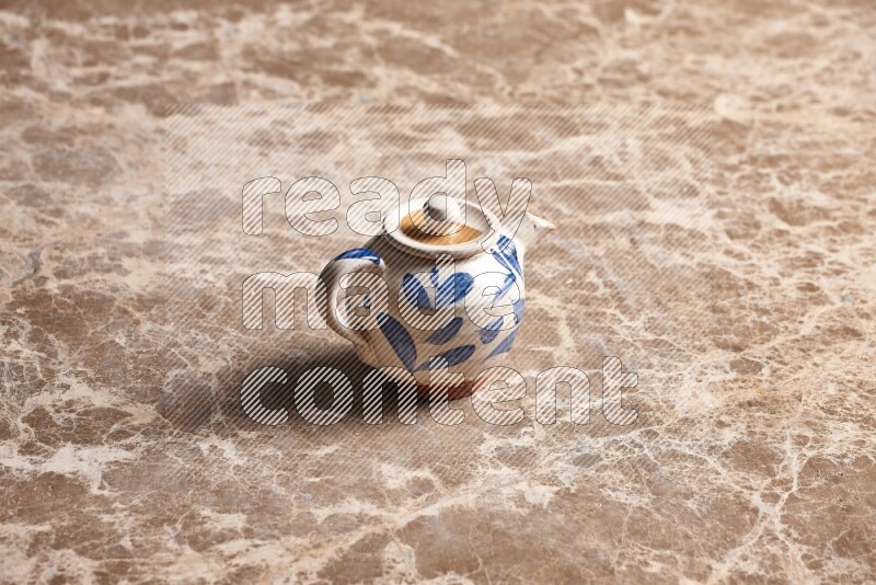 A pottery teapot on beige marble background