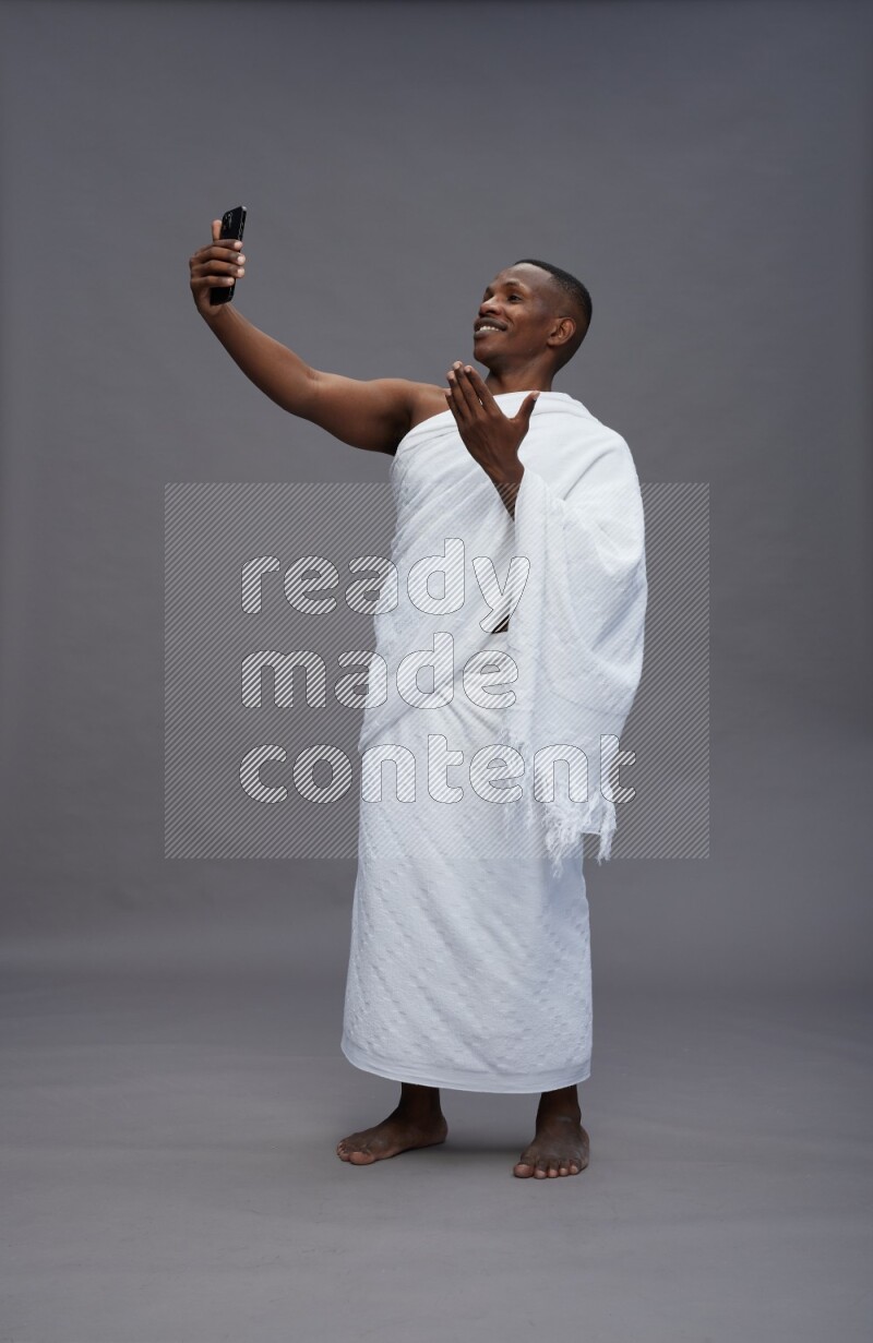 A man wearing Ehram Standing taking selfie on gray background