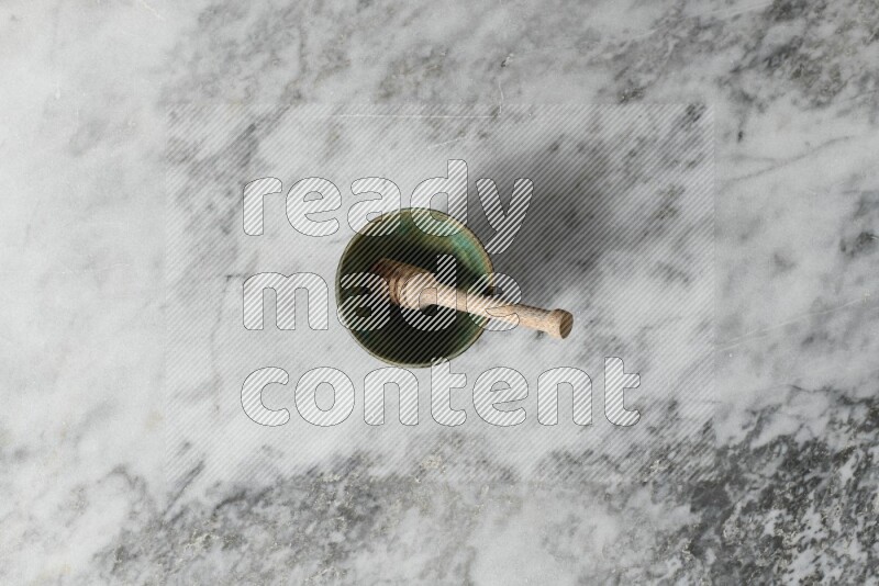 Multicolored pottery bowl with wooden honey dipper in it on grey marble background