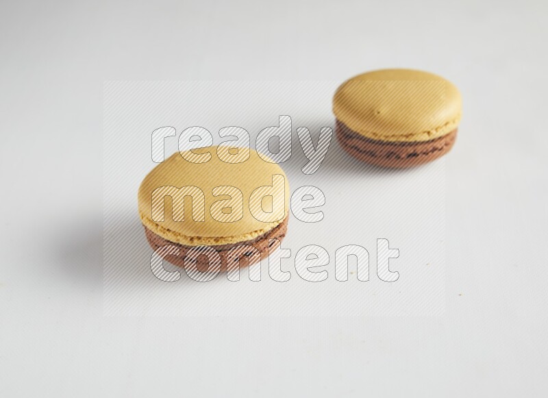 45º Shot of two Yellow and Brown Chai Latte macarons on white background