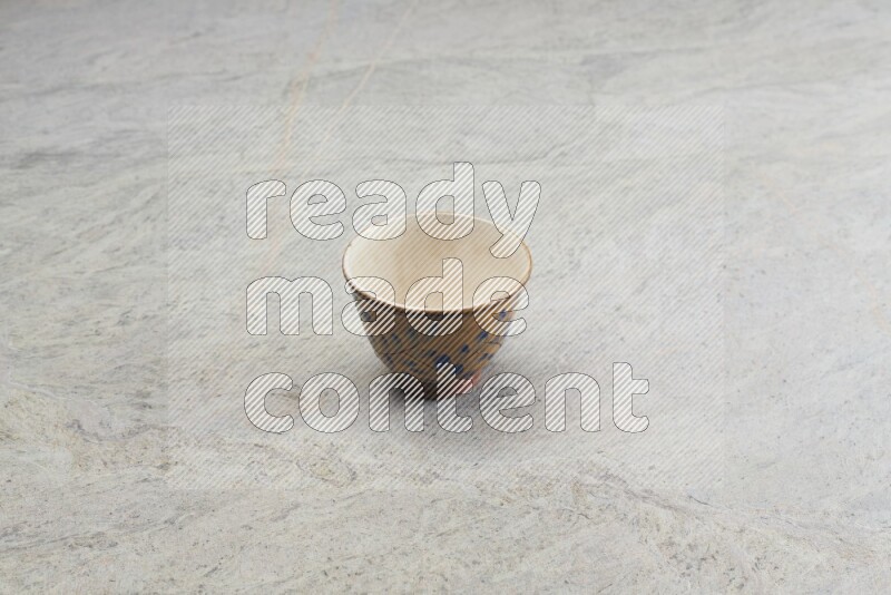 A multicolored pottery bowl on grey marble background