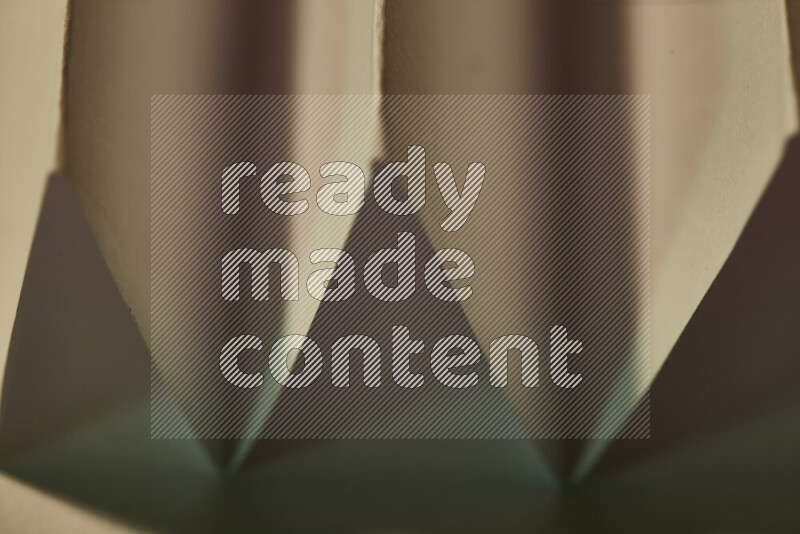 صورة مجردة مقربة تظهر طيات ورقية هندسية حادة بتدرجات اللون الأخضر مع درجات لونية دافئة