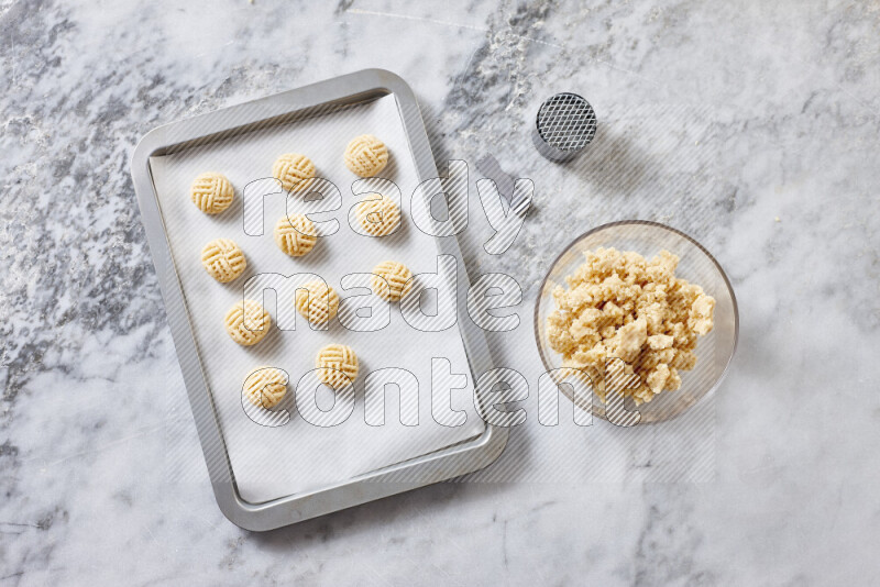 كحك خطوة بخطوة بمكوناته سمن، سكر، دقيق، سمسم، خميرة، ماء ونكهة الكحك على خلفية رخام رمادي