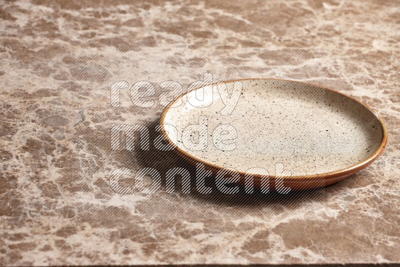 A multicolored pottery plate on beige marble background
