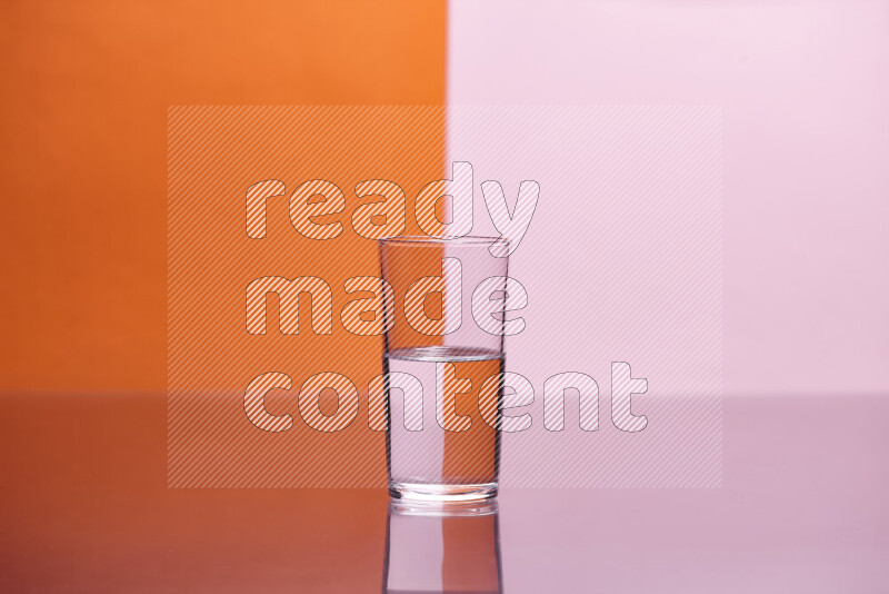 The image features a clear glassware filled with water, set against orange and rose background