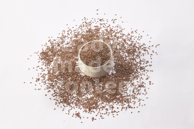 A pottery beige bowl full of flax seeds and more seeds spread on a white flooring