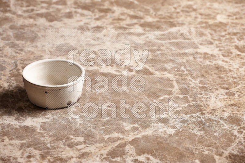 A white pottery bowl on beige marble background