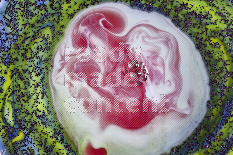 A close-up of swirls of red and white with sparkling purple glitter scattered on green and blue background