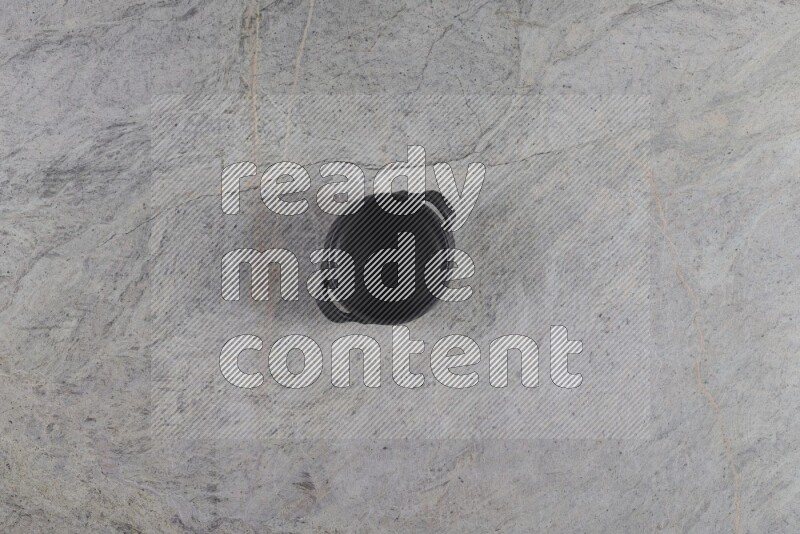 A black pottery bowl on grey marble background