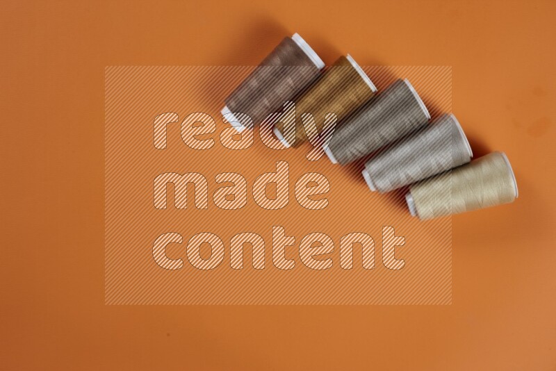 A brown collection of sewing and tailoring tools arranged on a orange background