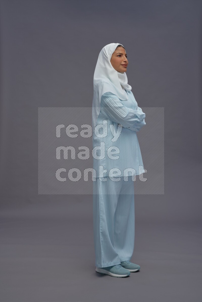 Saudi woman wearing hijab clothes standing with crossed arms on gray background