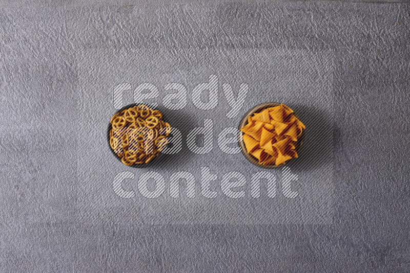 Assorted snacks in pottery bowls on grey background