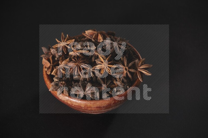 Star Anise in a wooden bowl on black flooring