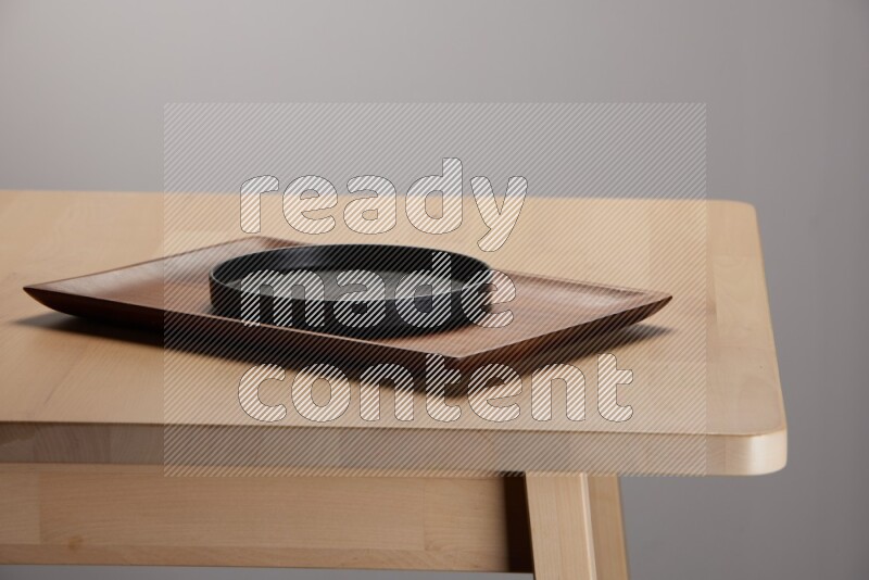 black plate on a rectangular wooden tray on the edge of wooden table