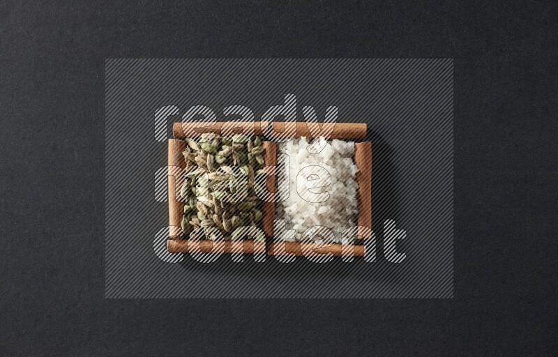 2 squares of cinnamon sticks full of white salt and cardamom on black flooring