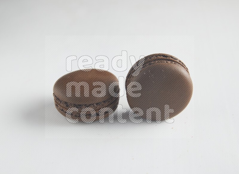 45º Shot of two Brown Dark Chocolate macarons on white background