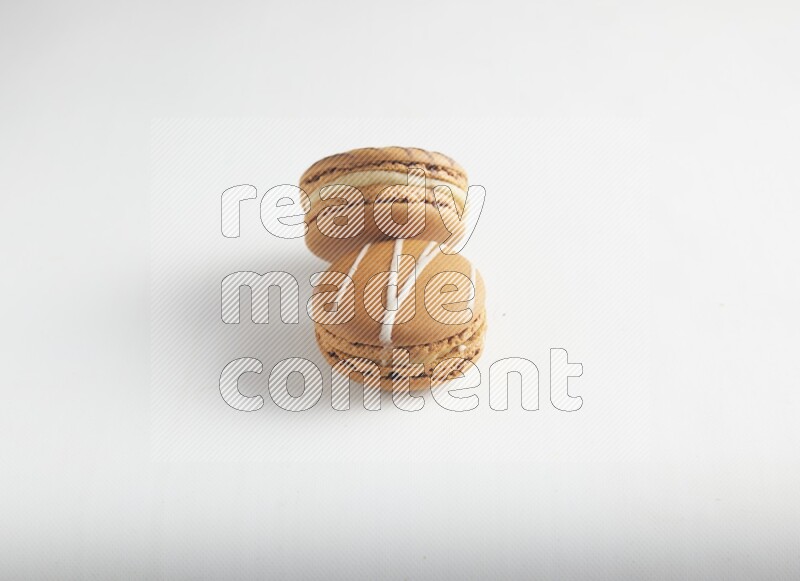 45º Shot of of two assorted Brown Irish Cream, and light brown  Almond Cream macarons on white background