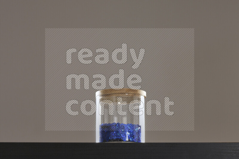 Sequins in a glass jar on black background