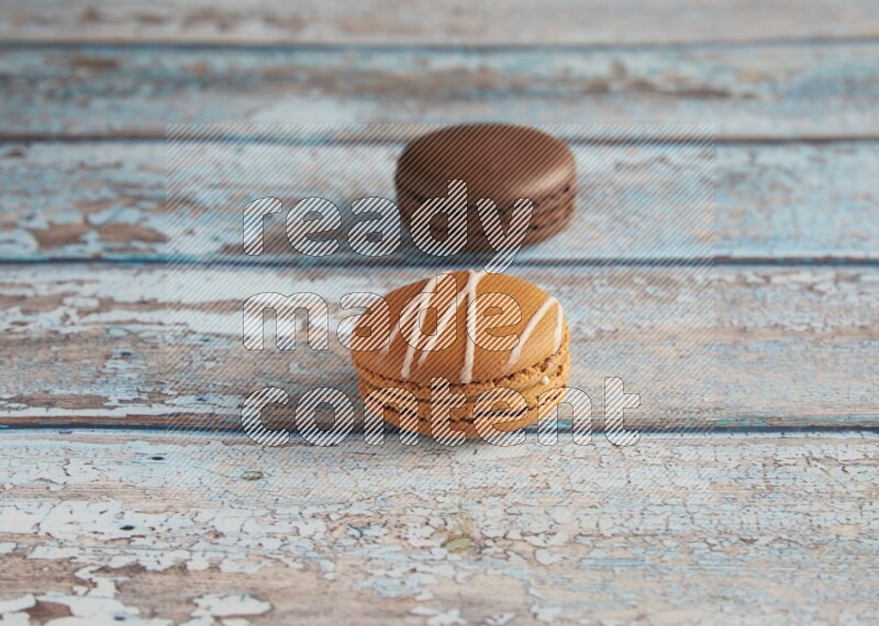 45º Shot of of two assorted Brown Irish Cream, and Brown Dark Chocolate macarons on light blue background