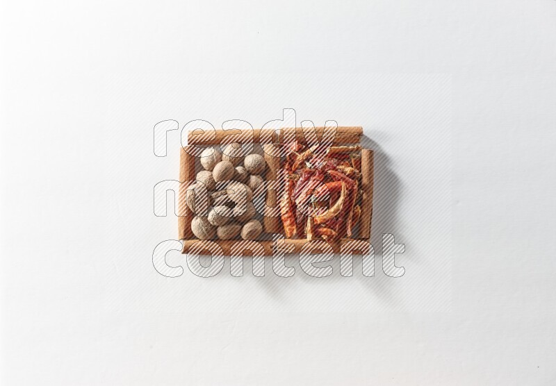 2 squares of cinnamon sticks full of dried red chilis and nutmegs on white flooring