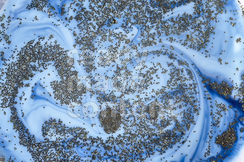 لقطة مقربة لبريق ذهبي متلألئ منتشر على خلفية من اللون الأزرق في حركات دائرية