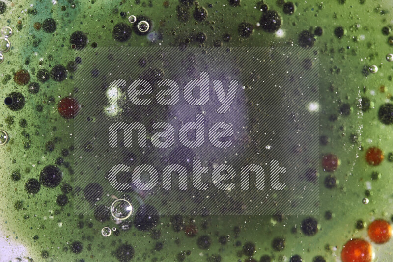 لقطات مقربة لقطرات ألوان مائية حمراء وخضراء وزرقاء على سطح الزيت على خلفية خضراء