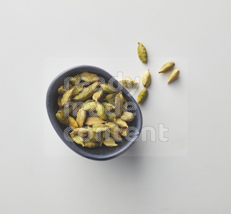 Top-view shot of Cardamon in a container on white background