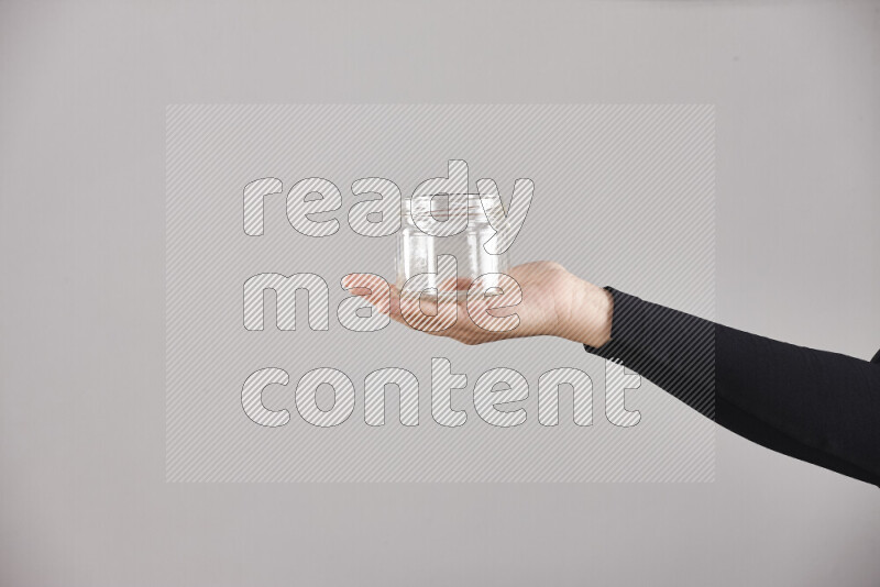 A woman in black abaya holding different glassware in different positions