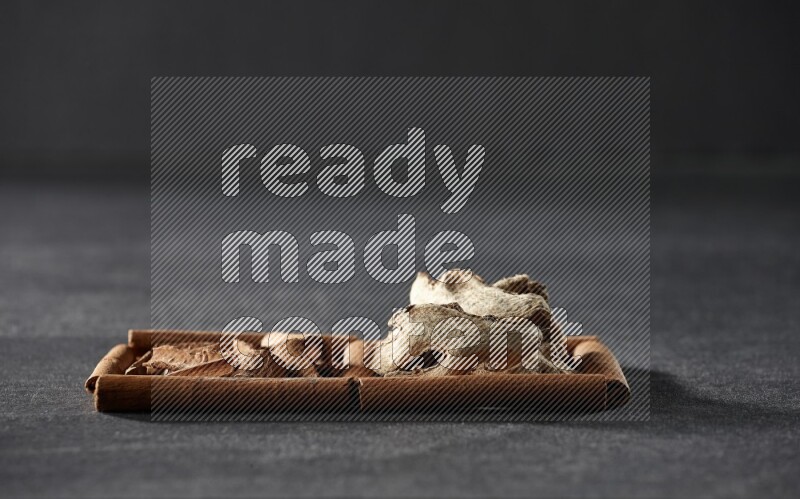 2 squares of cinnamon sticks full of cinnamon and ginger on black flooring