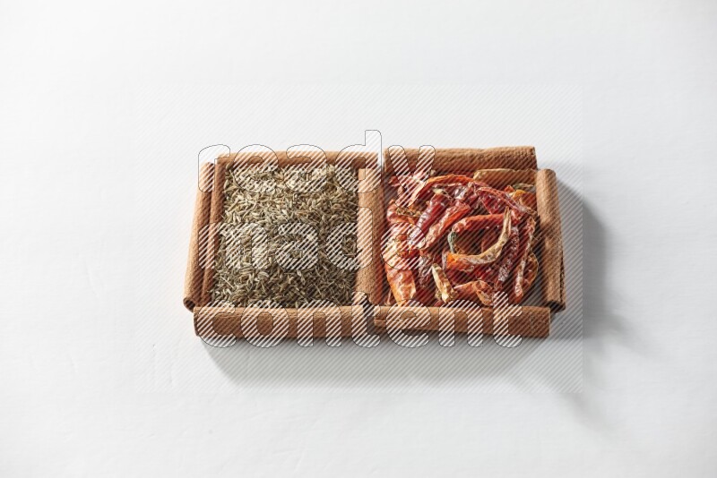 2 squares of cinnamon sticks full of dried red chilis and cumin on white flooring