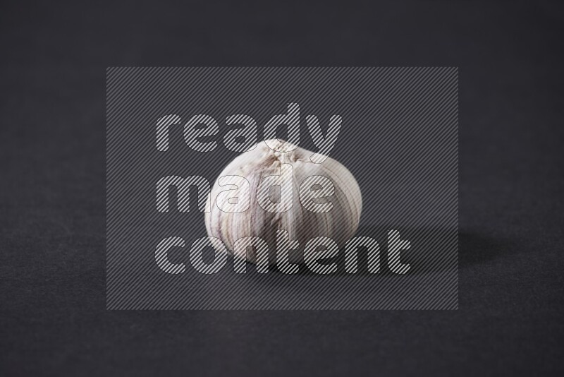 A whole garlic bulb placed on a black flooring