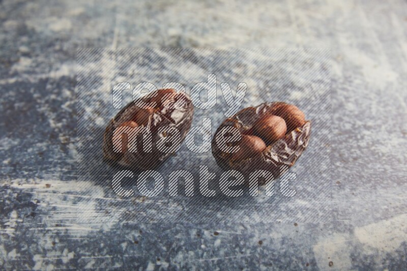 two hazelnuts stuffed madjoul dates on a rustic blue background