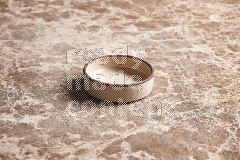 A beige pottery oven plate on beige marble background