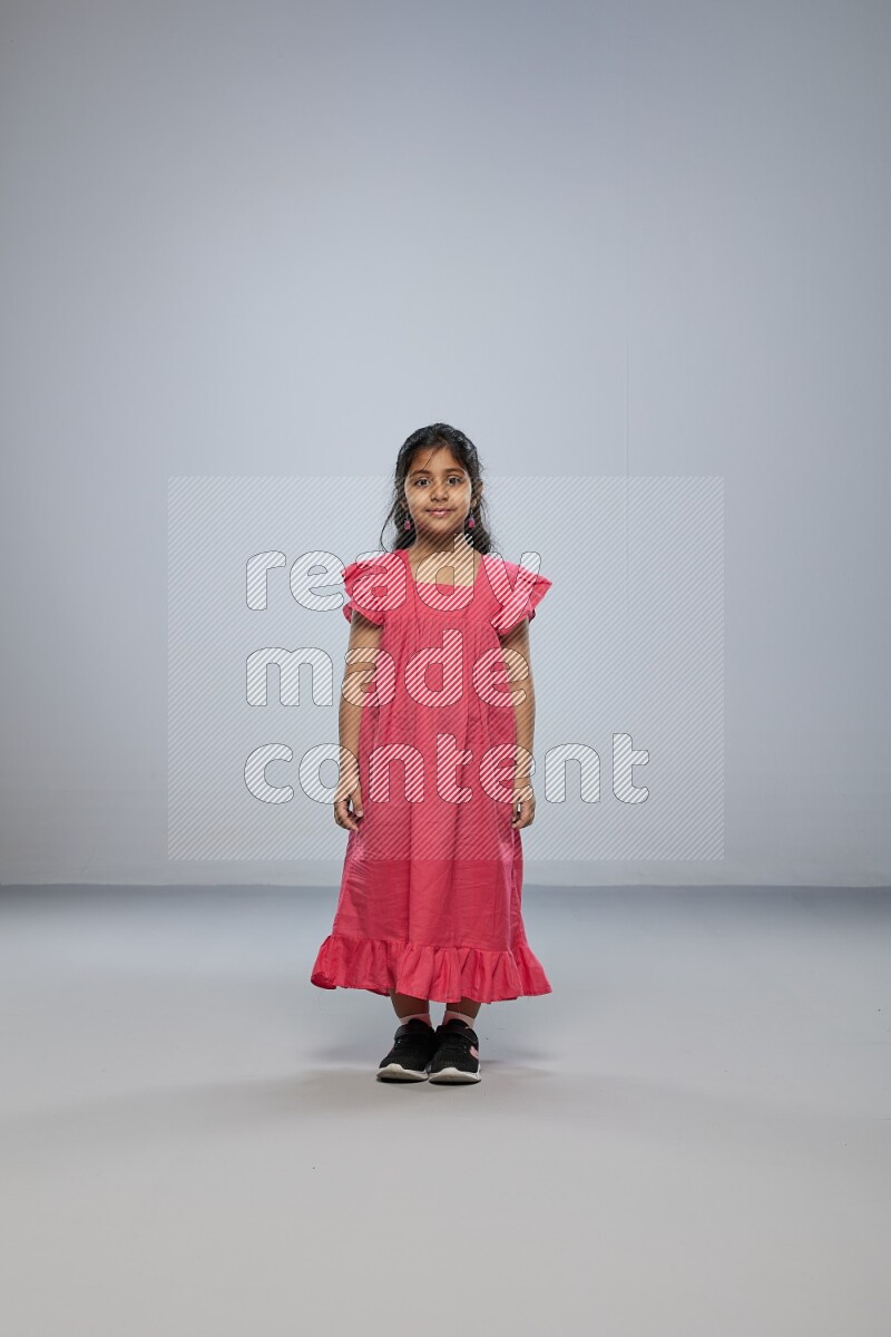 A girl standing interacting with the camera on gray background