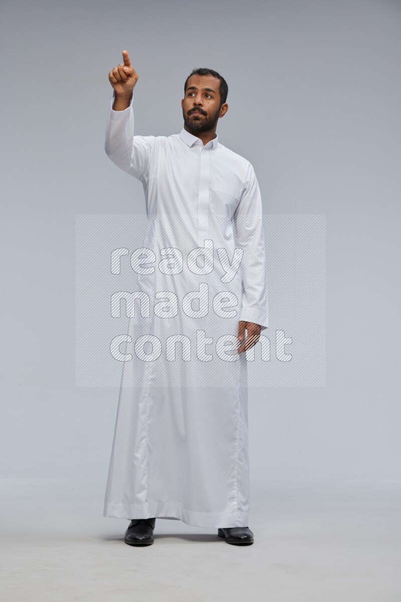 Saudi man Wearing Thob standing interacting with the camera on Gray background