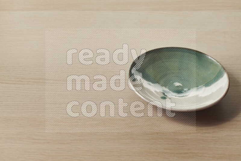 A multicolored pottery plate on light wooden background