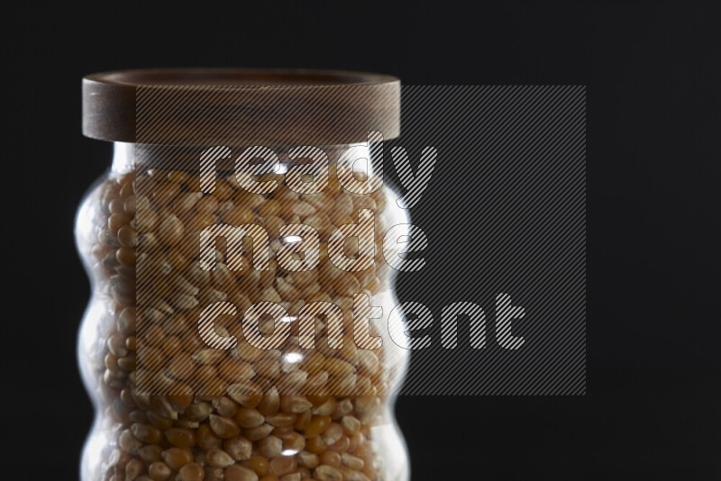 Pop corn in a glass jar on black background