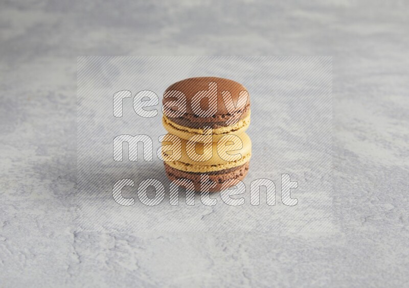 45º Shot of two Yellow and Brown Chai Latte macarons r on white  marble background