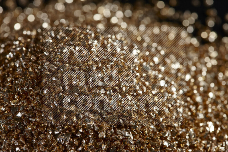 Gold shimmering fragments of glass scattered on a black background