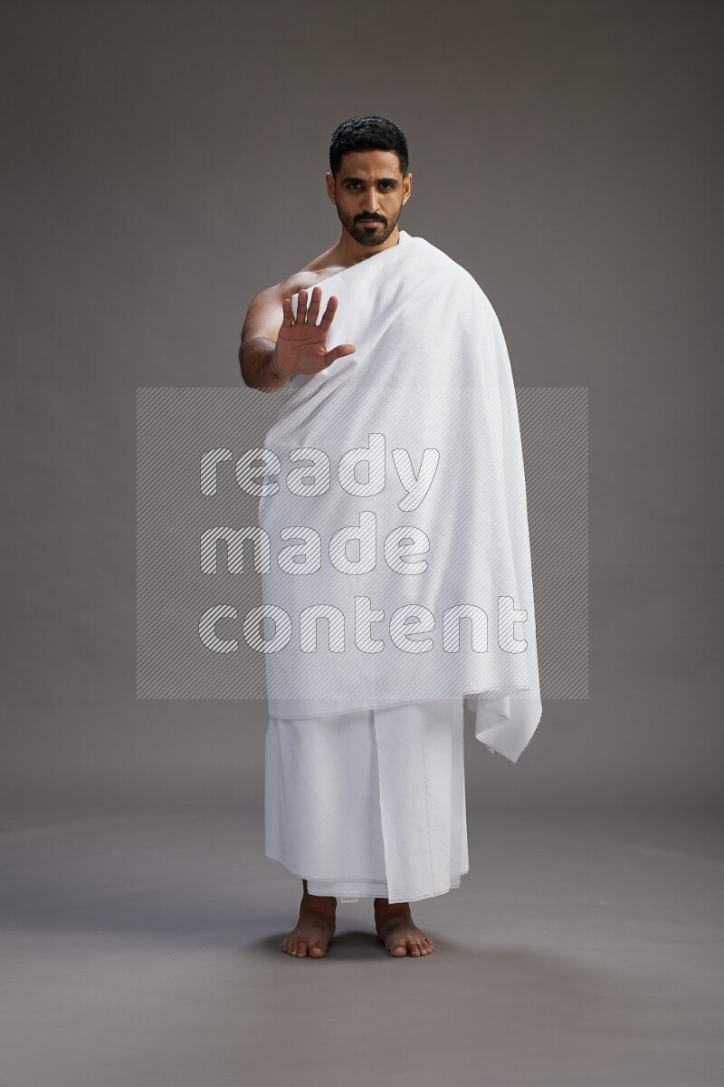 A man wearing Ehram Standing Interacting with the camera on gray background