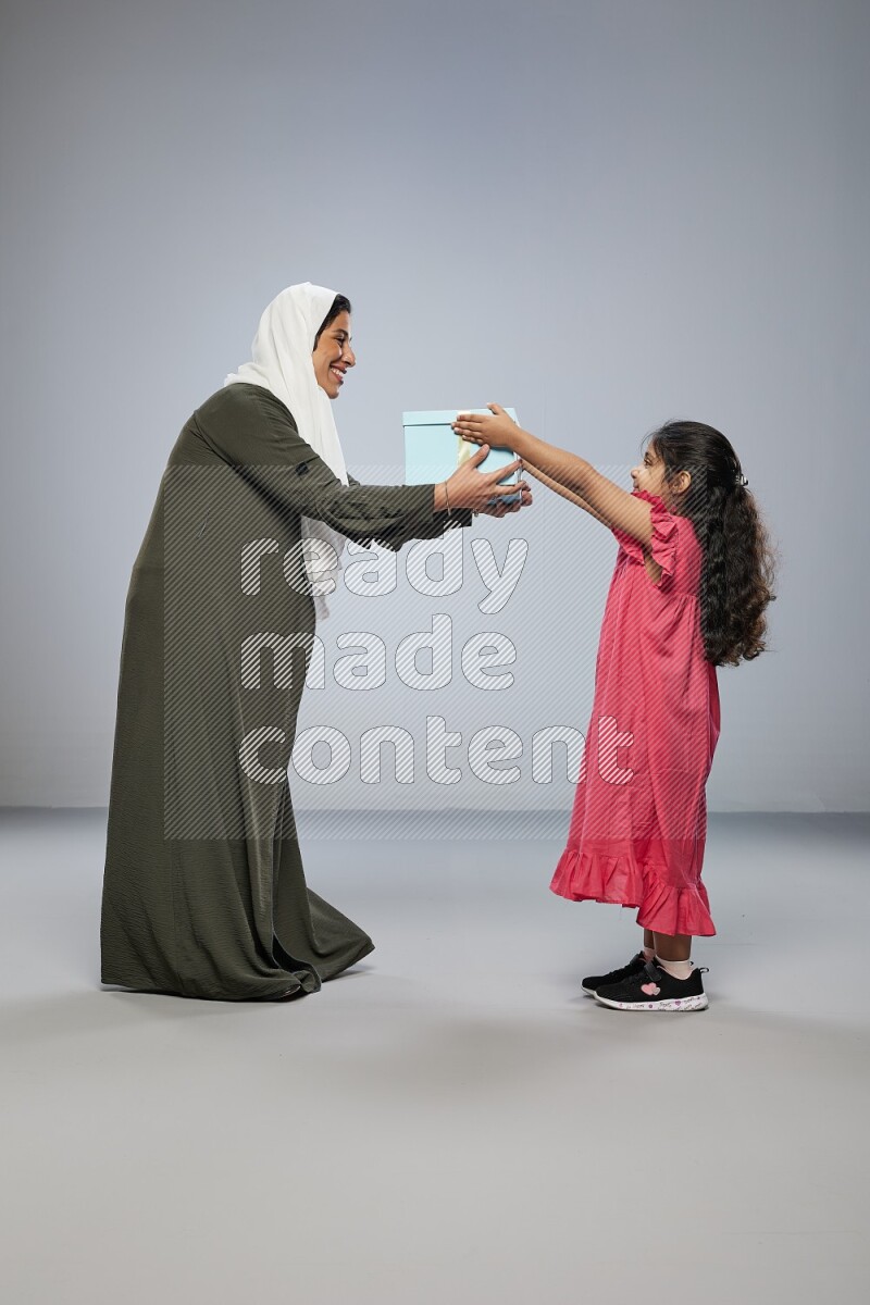 A girl giving a gift to her mother on gray background