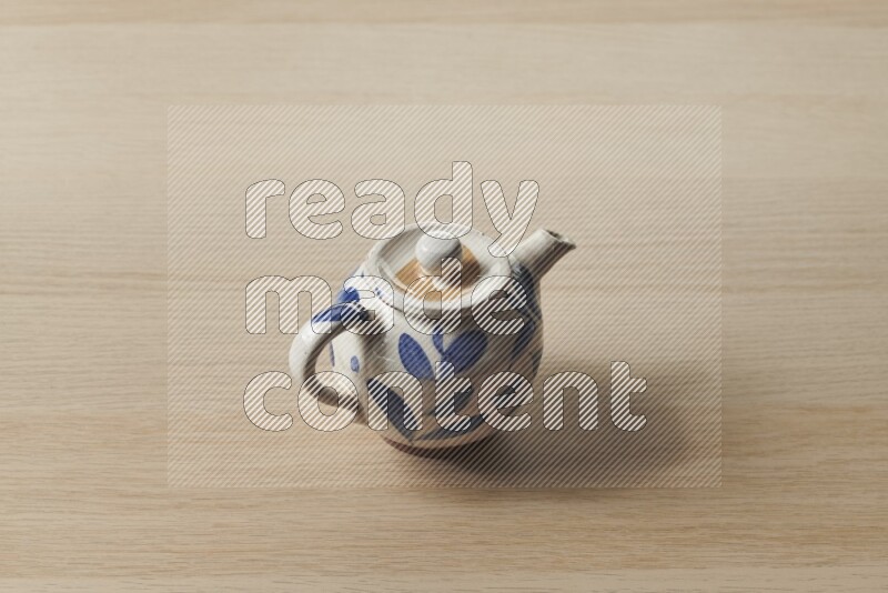 A pottery teapot on light wooden background