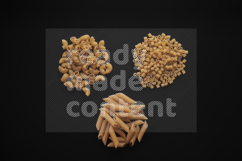 Different pasta types in bunches on black background