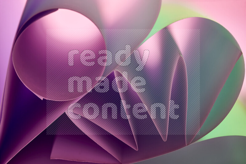 An artistic display of paper folds creating a harmonious blend of geometric shapes, highlighted by soft lighting in green and purple tones
